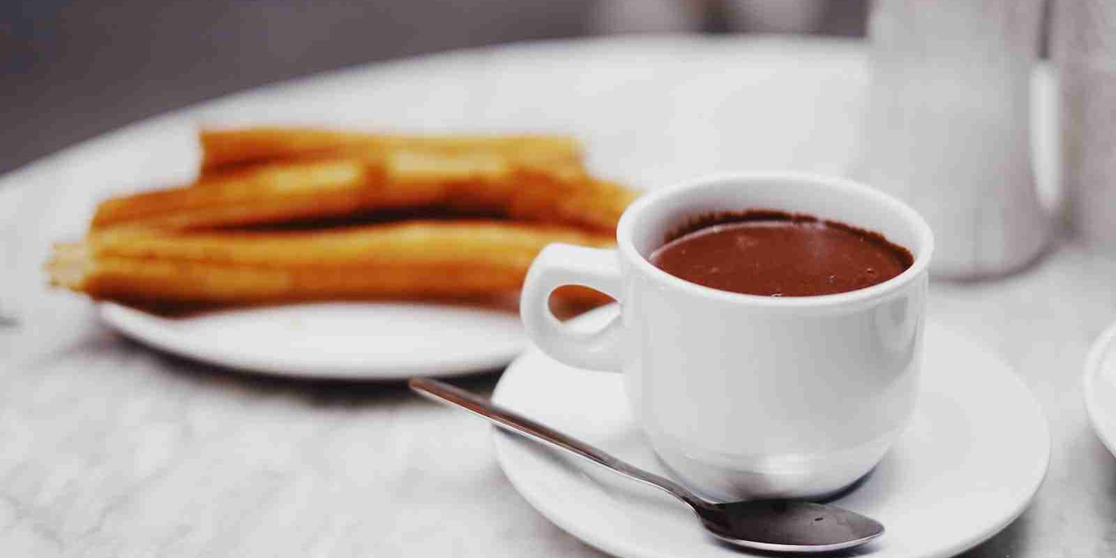 cup of chocolate drink with plate of churros