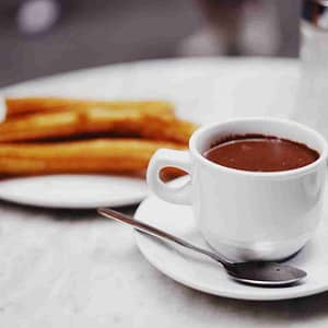 cup of chocolate drink with plate of churros