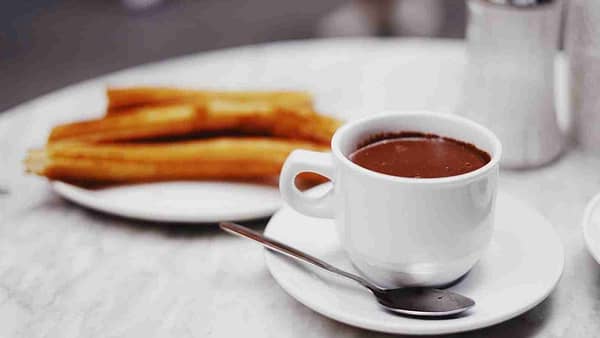 cup of chocolate drink with plate of churros